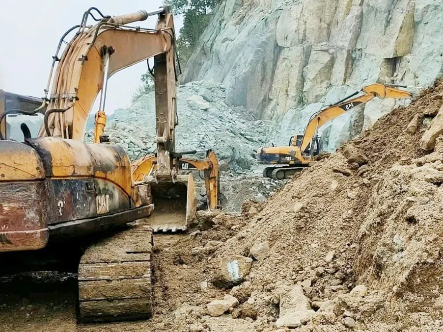 Excavators extracting raw andesite stone at the Sukabumi Regency quarry, West Java, Indonesia